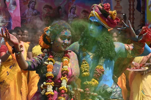 Youths smeared in coloured powder and dressed as Lord Krishna (R) and deity Radha (L) celebrate with others the Holi festival, the Hindu spring festival of colours, in Kolkata on March 17, 2022. (Photo by Dibyangshu Sarkar/AFP Photo)