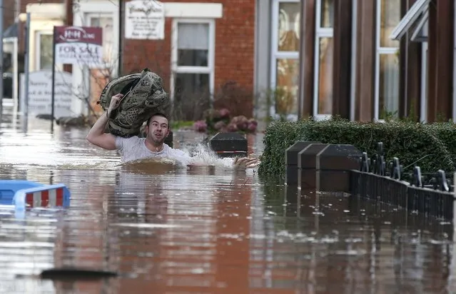 A local resident carries a bag as he wades through flood water on a residential street in Carlisle, Britain December 6, 2015. (Photo by Phil Noble/Reuters)