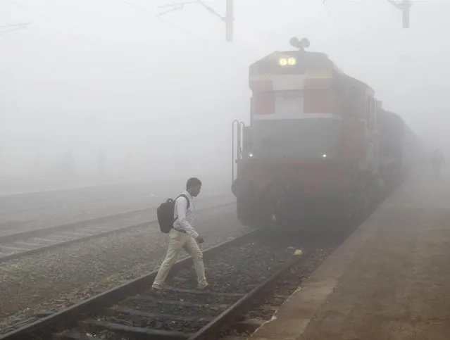 A man crosses a railway track next to a stationed train on a foggy morning in Allahabad, India, December 7, 2015. (Photo by Jitendra Prakash/Reuters)