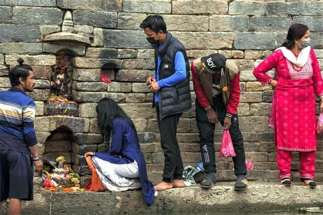 Hindu devotees queue up on a narrow ledge on the banks of the Bagmati river to offer prayers in front of an idol of Astamatrika, representing eight divine mother goddesses, at the Pashupatinath temple premises in Kathmandu, Nepal, Thursday, April 20, 2023. Nepalese Hindus on Thursday were marking Matatirtha Aunshi festival during which they pay tribute to their deceased mothers. (Photo by Niranjan Shrestha/AP Photo)
