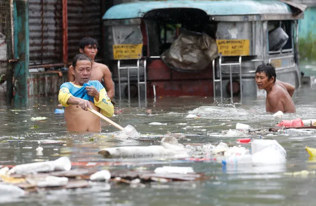 Residents gather plastics and other recyclabble materials along a flooded street caused by monsoon rains and Tropical Storm Son-Tinh in Quezon city, Metro Manila, Philippines on July 17, 2018. (Photo by Erik De Castro/Reuters)