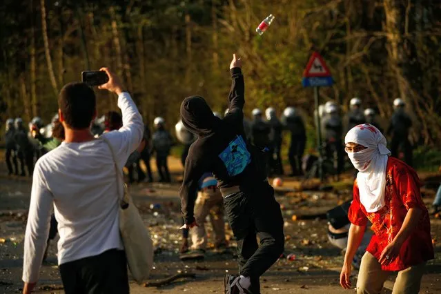 Protesters throw bottles towards police during protests in Brussels, Thursday, April 1, 2021. Belgian police have clashed with a large crowd in one of Brussels' biggest parks. Thousands of revellers had gathered for an unauthorized event despite coronavirus restrictions. (Photo by Fran Seco/AP Photo)