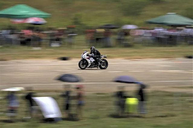 A motorcyclist pulls ahead of his competitors in a drag race at an old, unused airstrip in San Nicolas de Bari, Cuba, Sunday, July 23, 2023. (Photo by Ramon Espinosa/AP Photo)