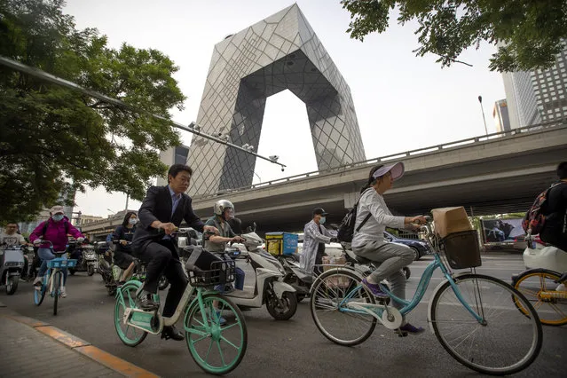 People ride bicycles past the China Central Television (CCTV) headquarters building in Beijing, Wednesday, May 19, 2021. Israel's Embassy in China is protesting what it describes as “blatant anti-Semitism” on a program run by the overseas channel of state broadcaster CCTV discussing the ongoing violence in Gaza and elsewhere. (Photo by Mark Schiefelbein/AP Photo)