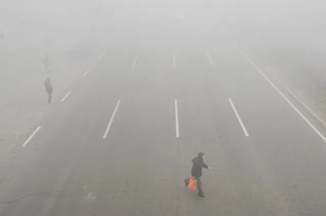 People walk across a road in smog during a polluted day in Tianjin, China, December 19, 2016. (Photo by Reuters/Stringer)