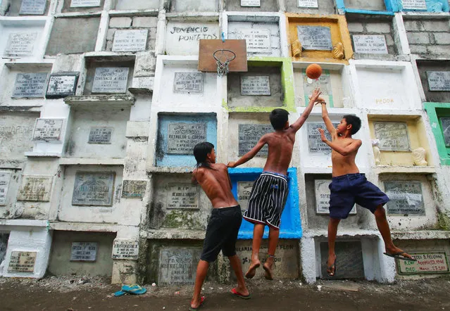 Filipino boys play basketball at an improvised court hooked on multi-layered tombs at a public cemetery in Navotas, north of Manila, Philippines on Thursday Oct. 31, 2013. Filipinos are expected to flock to cemeteries on November 1 to remember their dead as they observe All Saints Day in this predominantly Roman Catholic country. (Photo by Aaron Favila/AP Photo)