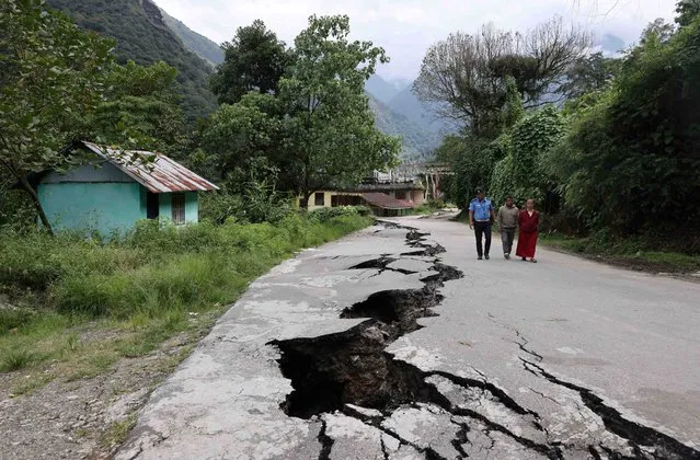 People walk along a road with cracks caused by flash floods in Naga-Namgor village, Sikkim, India on October 10, 2023. (Photo by Francis Mascarenhas/Reuters)