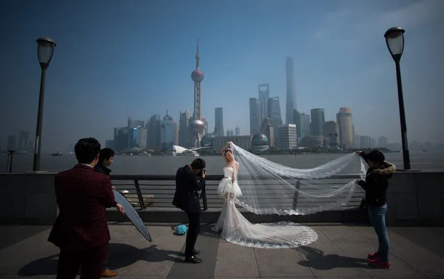 A woman poses for a wedding picture at the Bund in front of the financial district of Pudong in Shanghai on a sunny day on March 19, 2015. (Photo by Johannes Eisele/AFP Photo)