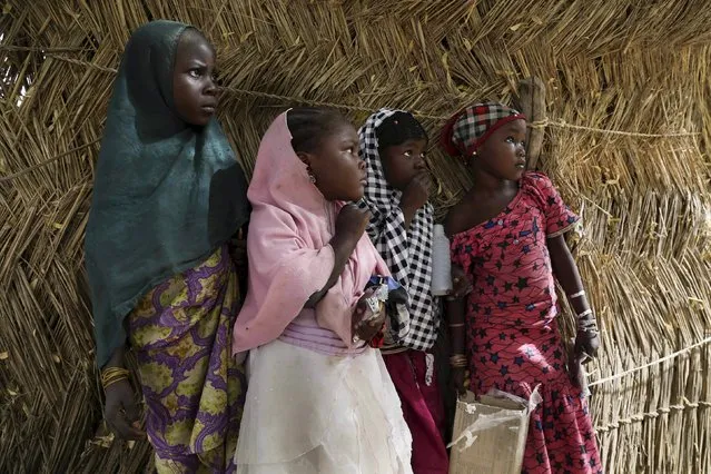 Girls watch soldiers from Niger and Chad in the recently retaken town of Damasak, Nigeria, March 20, 2015. Soldiers from Niger and Chad who liberated the Nigerian town of Damasak from Boko Haram militants have discovered the bodies of at least 70 people, many with their throats slit, scattered under a bridge, a Reuters witness said. (Photo by Emmanuel Braun/Reuters)