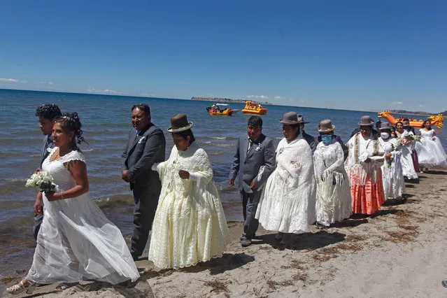 Couples are seen during a mass wedding ceremony where fifty couples got married at the shore of lake Titicaca in the Aymara district of Acora in Puno, Peru, on August 20, 2022. The public act was organized by the local municipality and held applying a mixture of modern and ancestral Andean customs, including the presence of their native Yatiri (Shaman) who made a payment to the Pachamama (Mother Earth) to wish good to the couples. (Photo by Carlos Mamani/AFP Photo)