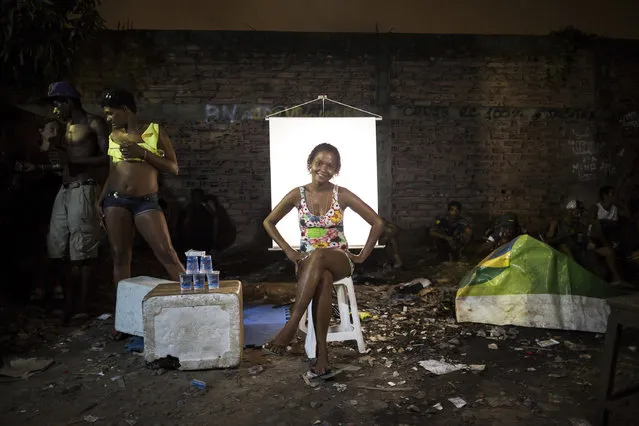 In this March 18, 2015, photo, Carla Cristina, 26, poses for a portrait next to her water stand in an open-air crack cocaine market, known as a “cracolandia” or crackland, where users can buy crack, and smoke it in plain sight, day or night, in Rio de Janeiro, Brazil. Carla Cristina sells cups of water with an aluminum seal, which users will transform into makeshift pipes for smoking their crack. (Photo by Felipe Dana/AP Photo)