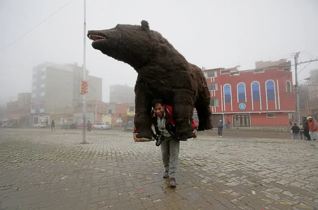 Street photographer Alfredo Vargas carries a replica of Baloo, a character from “The Jungle Book”, which he uses as a prop to take pictures of people in the street, in El Alto, on the outskirts La Paz, Bolivia, January 7, 2017. (Photo by David Mercado/Reuters)