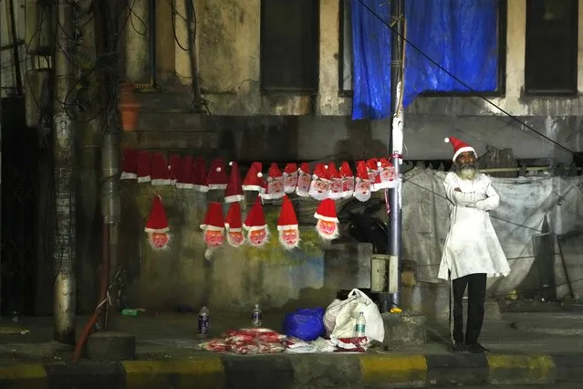 A street vendor selling Santa hats and masks waits for customers at an intersection in Hyderabad, India, Thursday, December 21, 2023. (Photo by Mahesh Kumar A./AP Photo)