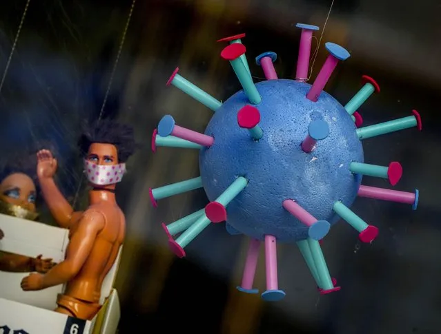 An oversize makeshift Coronavirus and plastic dolls decorated the window of a hairdresser in Frankfurt, Germany, Monday, September 13, 2021. (Photo by Michael Probst/AP Photo)