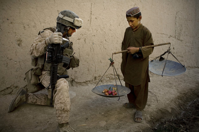 In this November 3, 2010 file photo, First Sgt. Yomen English, of Brookland, Ark., with India company, 3rd Battalion 5th Marines, First Marine Division, talks to a boy during a patrol, in Sangin, Afghanistan. (Photo by Dusan Vranic/AP Photo/File)