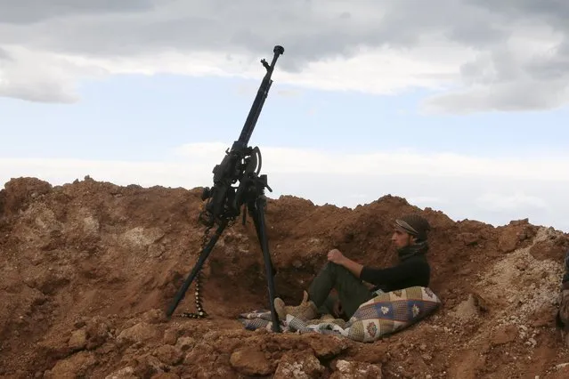 A rebel fighter sits near a weapon in Al-Lataminah village, northern Hama countryside, Syria March 5, 2016. (Photo by Ammar Abdullah/Reuters)