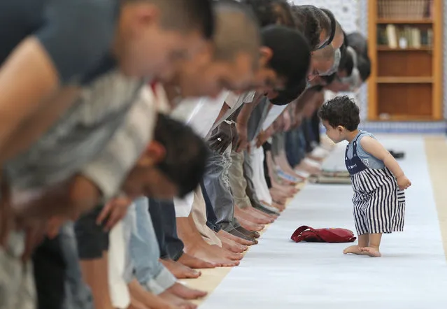 A child walks near members of the Muslim community attending midday prayers at Strasbourg Grand Mosque in Strasbourg on the first day of Ramadan July 9, 2013. (Photo by Vincent Kessler/Reuters)