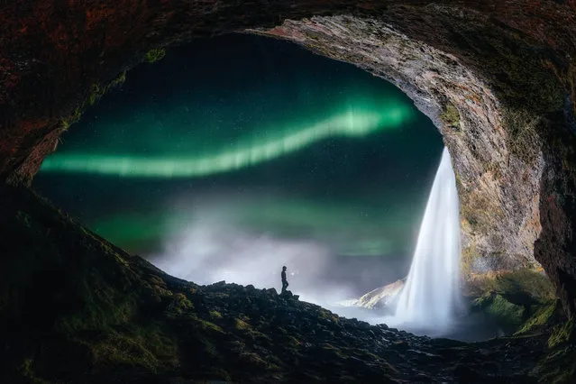 Aurora outside the tiny cave. Sutie Yang (China). The small cavern perfectly frames a mesmerising view of the aurora flaring up, the shining stars and the magnificent Seljalandsfoss waterfall on the south coast of Iceland. (Photo by Sutie Yang/National Maritime Museum)