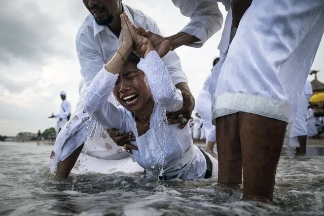 A woman cries while in a state of trance during the Melasti Ceremony at a beach in Badung, Bali, Indonesia, on March 28, 2014. (Photo by Agung Parameswara/Getty Images)