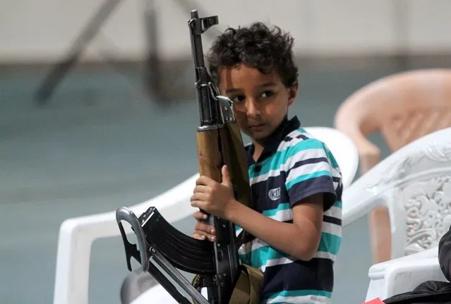 A boy holds a rifle while attending celebrations marking the 25th anniversary of Yemen's unification in Sanaa May 23, 2015. (Photo by Mohamed al-Sayaghi/Reuters)