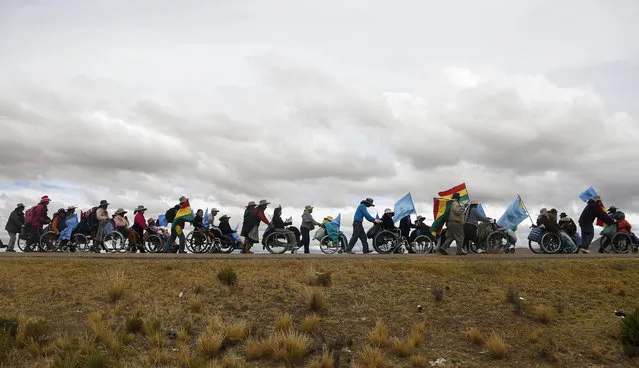 A group of people with disabilities take part in a protest march demanding an increase in their state benefits, and to receive monthly payments instead of one annual payment of 1,000 Bolivianos, or about  $145 U.S. dollars, in Patacamaya, Bolivia, Monday, April 18, 2016. The demonstrators began their march to the capital, leaving Cochabamba on March 21. They are asking the government increase their disability compensation to 500 Bolivianos, or about $73 dollars, per month. (Photo by Juan Karita/AP Photo)