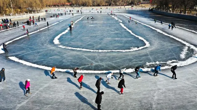 This aerial photo taken on January 11, 2022 shows residents skating on a frozen lake in Shenyang in China's northeastern Liaoning province. (Photo by AFP Photo/China Stringer Network)
