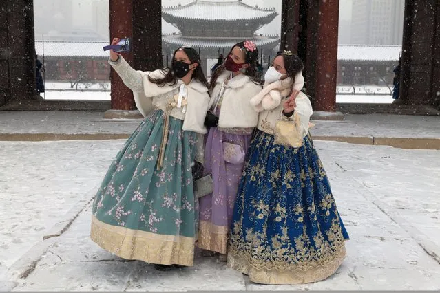 Mexican students living in Seoul, wearing face masks and traditional clothes, take selfies amidst snowfall during a visit to the​ Gyegbokgung Palace in Seoul, South Korea, 19 January 2022. (Photo by Jeon Heon-Kyun/EPA/EFE)