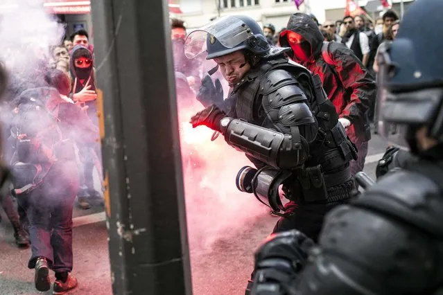 A policeman reacts during a clash with protestors during a protest against the proposed changes to France's working week and layoff practices, in Lyon, central France, Thursday, April 28, 2016. French protesters are back on the streets over proposed reforms to the country's labor rules and strikers have forced cancellations and delays at two airports serving Paris. (Photo by Laurent Cipriani/AP Photo)