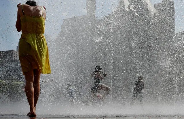 Kids and adults cool off in a fountain on the Rose Kennedy Greenway on the first day of a forecasted summer heatwave in Boston, Massachusetts, U.S., July 19, 2019. (Photo by Brian Snyder/Reuters)