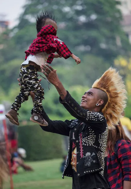 A member of a punk group plays with his one-year-old son as he and some of his friends gather in a park in central Yangon on April 12, 2017, on the eve of the water festival known as Thingyan. (Photo by Roberto Schmidt/AFP Photo)