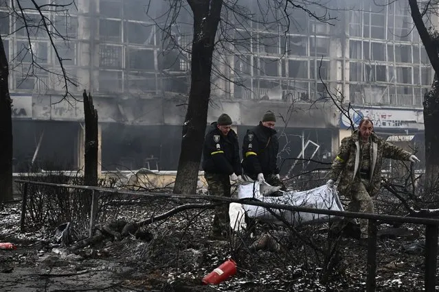 Police officers move the bodies of passersby killed in yesterday's airstrike that hit Kyiv's main television tower in Kyiv on March 2, 2022. An apparent Russian airstrike hit Kyiv's main television tower in the heart of the Ukrainian capital on March 1, 2022. (Photo by Aris Messinis/AFP Photo)