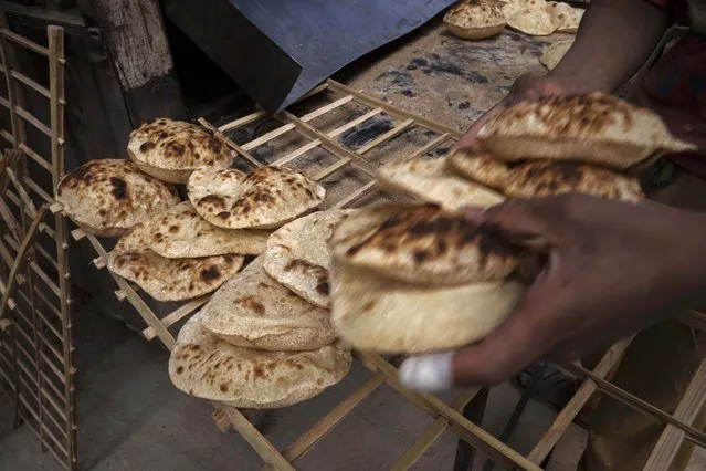 A worker collects Egyptian traditional “baladi” flatbread, at a bakery, in el-Sharabia, Shubra district, Cairo, Egypt, Wednesday, March 2, 2022. The Russian tanks and missiles besieging Ukraine also are threatening the food supply and livelihoods of people in Europe, Africa and Asia who rely on the vast, fertile farmlands of the Black Sea region. That could create food insecurity and throw more people into poverty in places like Egypt and Lebanon, where diets are dominated by government-subsidized bread. (Photo by Nariman El-Mofty/AP Photo)