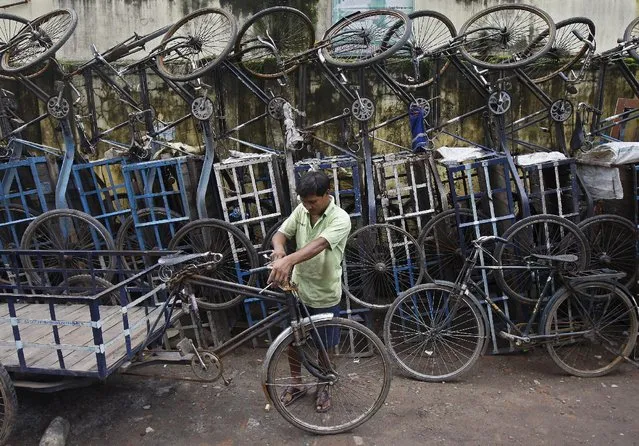 A mechanic tightens a nut of a cycle rickshaw at a parking area in Kolkata, India, July 24, 2015. (Photo by Rupak De Chowdhuri/Reuters)