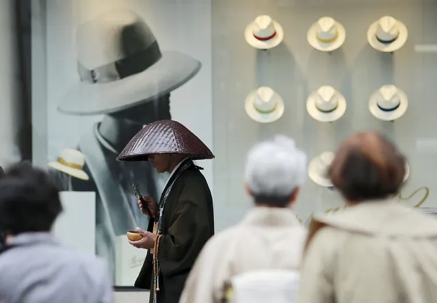 A Buddhist monk offers prayers in front of a window display of hats at a department store in the Ginza shopping district in Tokyo Tuesday, May 16, 2017. (Photo by Eugene Hoshiko/AP Photo)