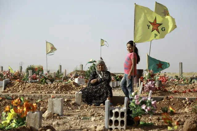 A Syrian Kurdish woman sits next to the grave of a relative during the funeral of fighters, who died during an assault launched by Arab and Kurdish forces against Islamic State (IS) group fighters in the town of Manbij, in the Syrian Kurdish town of Kobane on June 4, 2016. Arab and Kurdish fighters backed by Washington have launched an assault on the strategic Manbij pocket further up the Euphrates on the Turkish border, regarded as a key entry point for foreign jihadists. (Photo by Delil Souleiman/AFP Photo)