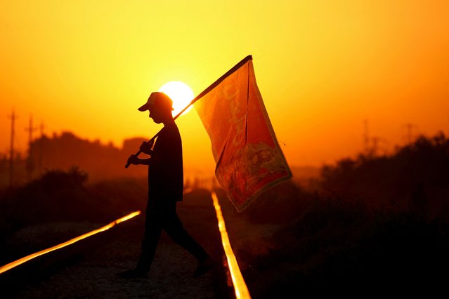 A shiite Muslim pilgrim marches with a banner towards the shrine city of Karbala ahead of the Arbaeen commemorations that mark the end of the 40-day mourning period for the seventh century killing of the Prophet Mohamed's grandson Imam Hussein ibn Ali, near the city of Hilla, in the central Babil Governorate on August 17, 2024. (Photo by Karar Jabbar/AFP Photo)