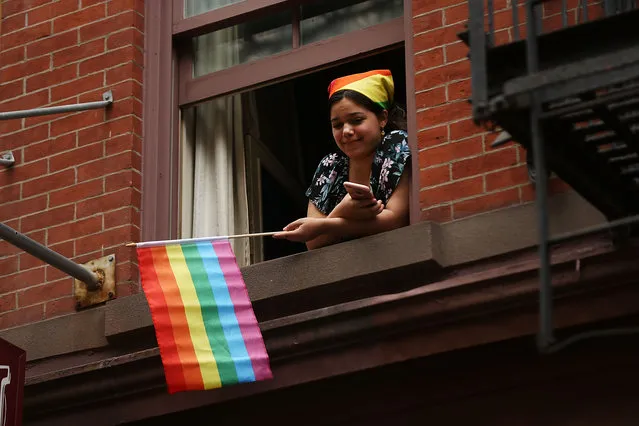 A woman watches as participants in the annual New York Gay Pride Parade, one of the oldest and largest in the world, march throughthe  West Village in Manhattan on June 25, 2017 in New York City. Thouands cheered as members of LGBT community danced and marched under a bright summer sun. Many participants carried political themed signs as President Trump's adminstration has angered some in the LGBT community. (Photo by Spencer Platt/Getty Images)