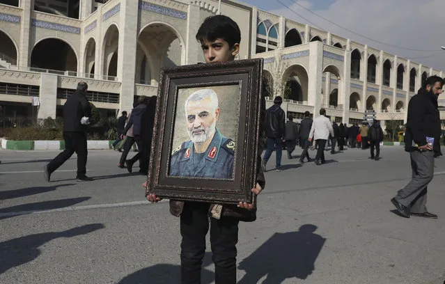 A boy carries a portrait of Iranian Revolutionary Guard Gen. Qassem Soleimani, who was killed in the U.S. airstrike in Iraq, prior to the Friday prayers in Tehran, Iran, Friday January 3, 2020. Iran has vowed “harsh retaliation” for the U.S. airstrike near Baghdad's airport that killed Tehran's top general and the architect of its interventions across the Middle East, as tensions soared in the wake of the targeted killing. (Photo by Vahid Salemi/AP Photo)