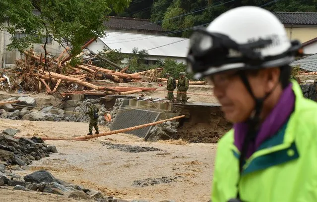 A Self-Defense Forces personnel crosses (L) a river in a disaster area following heavy flooding in Asakura, Fukuoka prefecture, on July 7, 2017. Huge floods engulfing parts of southern Japan are reported to have killed at least six people and left hundreds stranded as the torrents swept away roads and houses and destroyed schools. (Photo by Kazuhiro Nogi/AFP Photo)