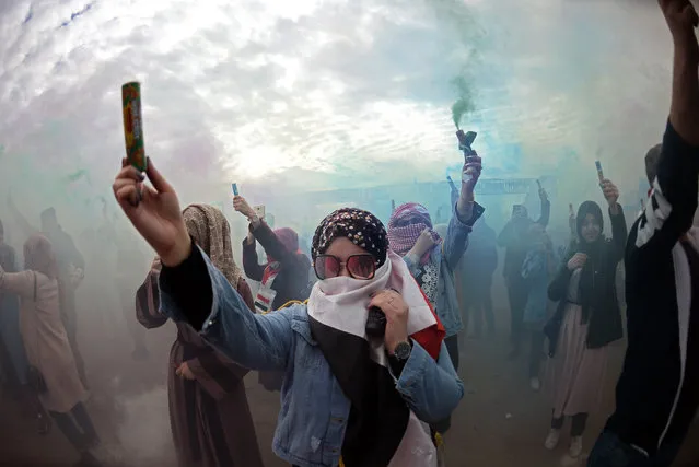 Iraqi demonstrators carry smoke cartridges, which release coloured smoke, during the first colour festival outside the Kufa University in the holy shrine city of Najaf on January 15, 2020. (Photo by Haidar Hamdani/AFP Photo)