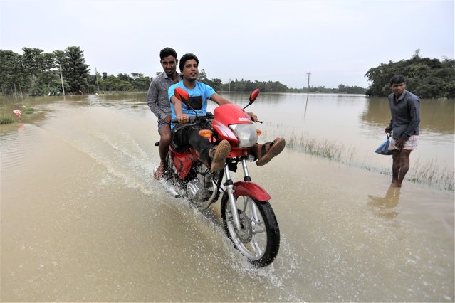 A motorist drives through a flooded road in Bagha area in Sylhet, Bangladesh, Monday, May 23, 2022. Pre-monsoon deluges have flooded parts of India and Bangladesh, killing at least 24 people in recent weeks and sending 90,000 people into shelters, authorities said Monday. (Photo by AP Photo/Stringer)