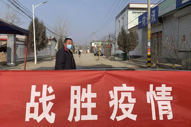 A man wearing a face mask stands near a banner reading “defeat the epidemic” stretched across the entrance to Donggouhe village in northern China's Hebei Province, Wednesday, January 29, 2020. With barricades and wary guardians, villages on the outskirts of Beijing are closing themselves off to outsiders to ward against infection amid the outbreak of a new type of virus. (Photo by AP Photo/Stringer)