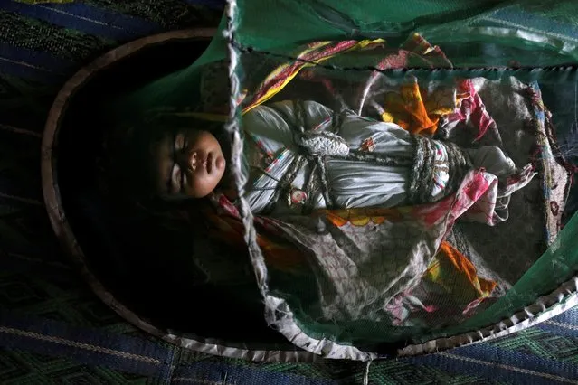One-month-old Vamar Kumar, sleeps at home under a mosquito net, during a heatwave, on the outskirts of Jacobabad, Pakistan, May 17, 2022. (Photo by Akhtar Soomro/Reuters)