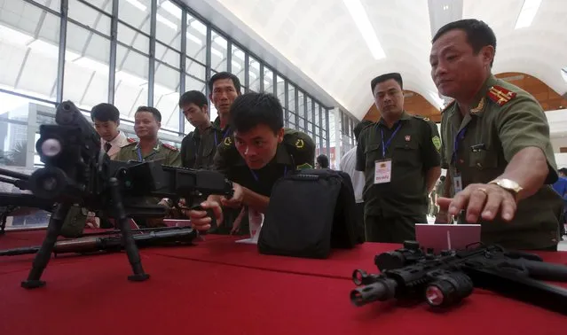 A commune policeman (C) demonstrates an Israeli-made CornerShot rifle during celebrations to commemorate the 70th anniversary of the establishment of the Vietnam Public Security police force at the National Convention Center in Hanoi August 18, 2015. (Photo by Reuters/Kham)
