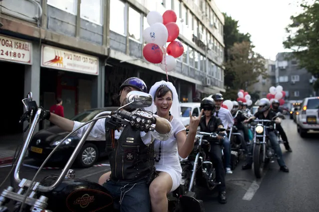 Bride Yulia Tagil sits on the backseat of a bike as she arrives for her alternative wedding ceremony on a square in Tel Aviv July 25, 2010. The alternative wedding ceremony was intended to demonstrate against the current situation in Israel, where the only way for Jews to get married by law is through the Chief Rabbinate. (Photo by Nir Elias/Reuters)