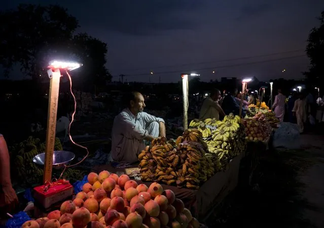 A Pakistani fruit vendor waits for customers at dusk in Islamabad, Pakistan, Tuesday, August 4, 2015. (Photo by B. K. Bangash/AP Photo)