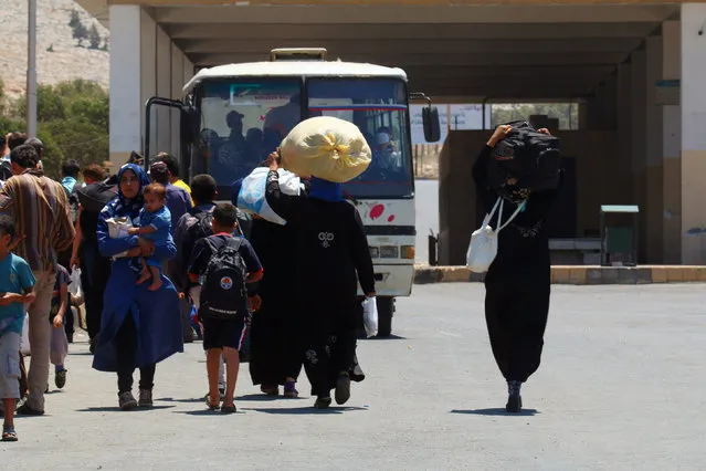 Syrians carry their belongings as they cross back into Syria at the Syrian-Turkish border crossing in Bab al-Hawa in Idlib province, Syria July 1, 2016. Turkish authorities announced the opening of its border crossing with Syria, allowing Syrians living in Turkey to celebrate the Muslim religious holiday of Eid al-Fitr with their families living inside Syria. (Photo by Ammar Abdullah/Reuters)