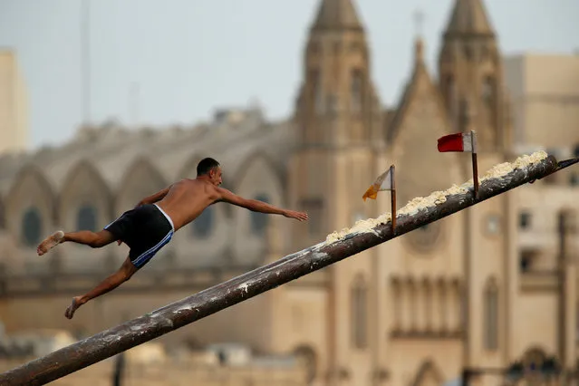 A competitor tries to grab a flag on the “gostra”, a pole covered in lard, as he falls off it during the celebrations for the religious feast of St Julian, patron of the town of St Julian's, Malta, August 20, 2017. (Photo by Darrin Zammit Lupi/Reuters)