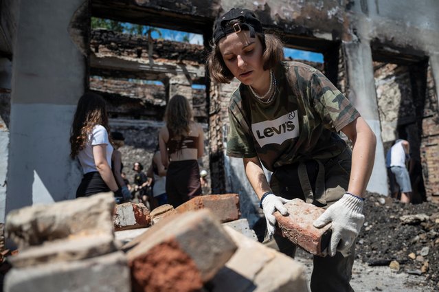 Volunteers remove debris from the House of a Culture in the village of Yahidne, which was heavily damaged during Russia's attack on Ukraine, in Chernihiv region, Ukraine on July 23, 2022. (Photo by Viacheslav Ratynskyi/Reuters)