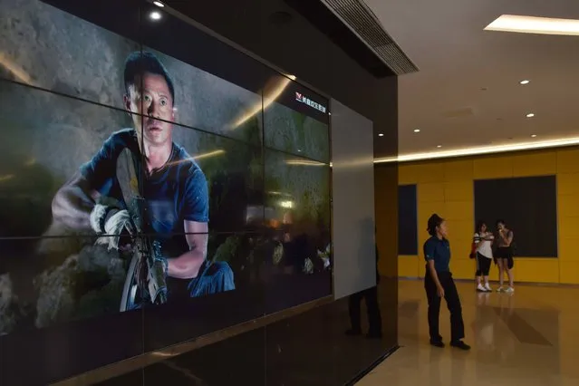 A woman walks past a video screen showing scenes from the movie “Wolf Warrior 2” outside a theater in Beijing on August 21, 2017. Fresh from shattering China's box-office record, patriotic blockbuster “Wolf Warriors 2” has claimed another slice of history by becoming the first non-Hollywood film to break into the top 100 all-time grossing movies worldwide. (Photo by Greg Baker/AFP Photo)